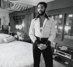 a black and white photo of a man standing in front of a bed with the name coco on it