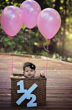 a baby sitting in a basket with balloons