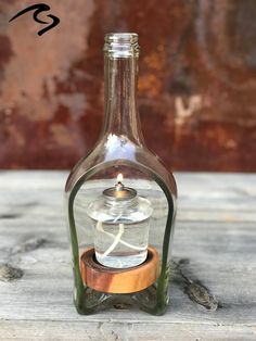 a glass bottle with a wooden base and a small candle in it's top