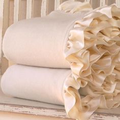 two sheets with ruffles on them sitting on a table next to a wall