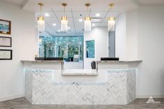 the front desk of a dental office with lights on and marble counter top, along with framed pictures