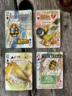 four playing cards with birds on them sitting next to each other in front of a piece of wood