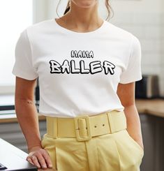 a woman wearing a white shirt with the word'mama baller'printed on it