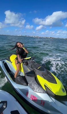 a woman sitting on the back of a yellow and black jet ski in the ocean