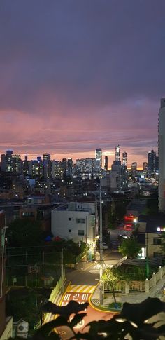 the city skyline is lit up at night, with buildings in the foreground and cars on the street