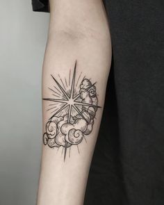 a black and white tattoo design on the left arm with clouds, stars and sunburst