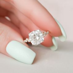 a woman's hand holding a ring with a diamond on it and a white manicure