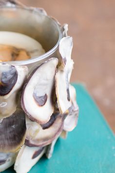 a vase filled with lots of clams sitting on top of a blue tablecloth