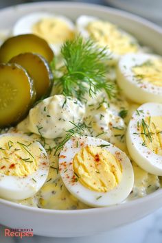 an egg salad with pickles and dill on the side in a white bowl