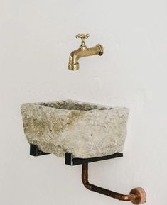 a bathroom sink with a gold faucet on the wall next to it and a soap dispenser