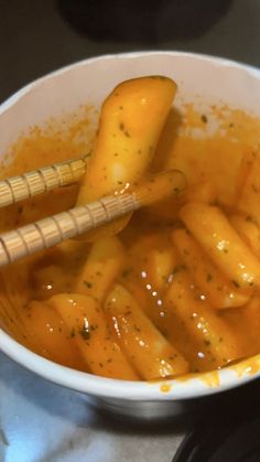 a white bowl filled with orange sauce and two wooden utensils