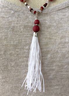 This handmade necklace and earrings set is made from a handmade white tassel with red dyed wood beads; semiprecious red jade faceted teardrops; glass seeds beads in brown, burgundy red, and white; and silver-tone components. White Tassel Earrings Gift, Gift White Tassel Earrings, Red Tassel Necklaces As Gifts, Red Tassel Necklaces For Gifts, Red Tassel Necklace For Gift, White Round Beads Tassel Earrings Gift, White Tassel Jewelry With Round Beads, White Round Beaded Tassel Jewelry, Adjustable White Tassel Necklace Gift