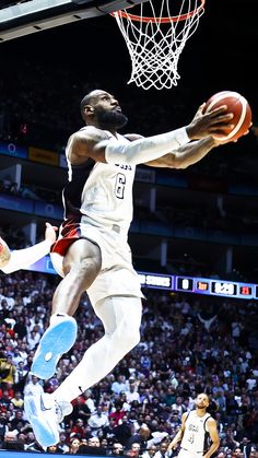 a basketball player jumping up into the air to dunk a ball in front of an audience