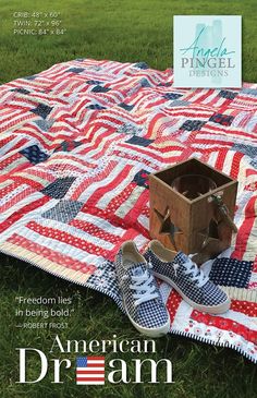 an american dream quilt on the grass with tennis shoes and a box sitting on it