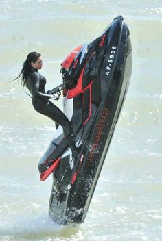 a woman in black wetsuit holding onto a jet ski