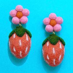 two needled strawberry earrings with pink flowers on each earring and green leaves hanging from them