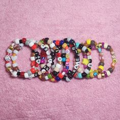 several bracelets with letters on them sitting on a pink towel