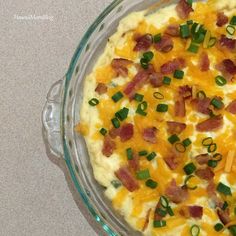 a casserole dish with cheese, bacon and green onions