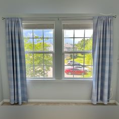 two windows with blue and white checkered curtains in front of them, one has a red car on the window sill