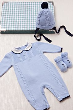 a baby's blue outfit and booties on a table