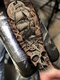 a man's arm with a ship on it and skull in the foreground