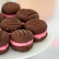 chocolate and pink frosted cookies on a white plate