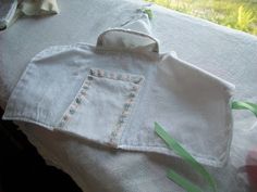 a baby's bib is laying on top of a white sheet with green ribbon