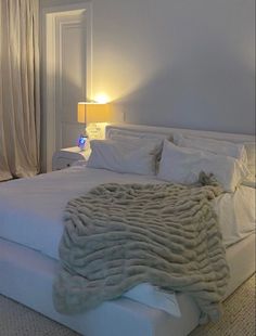 a large bed with white sheets and blankets on it's headboard in a bedroom