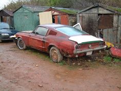 an old rusted car parked in front of some shacks