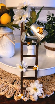 a table topped with white vases filled with flowers and lemons on top of a wooden ladder