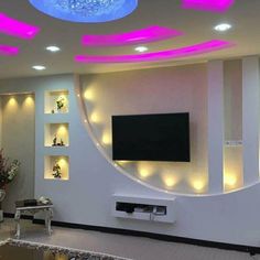 a living room with white walls and pink lights on the ceiling, along with built - in shelving