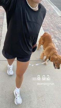 a woman is walking her dog down the sidewalk with it's tongue hanging out