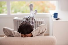 a person laying down on a couch with their feet up in front of the heater