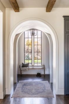 an arched entryway with a bench in the center and large windows on both sides