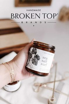 a hand holding a jar of sea salt sits on a table