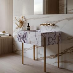 a marble sink in a bathroom with gold legs