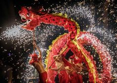 people in red and yellow costumes are performing with firecrackers as fireworks go off behind them