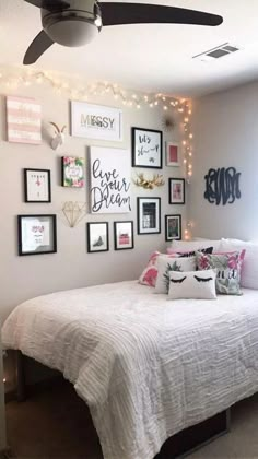 a bedroom with pictures on the wall and a white bed in front of a ceiling fan