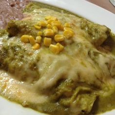 a white plate topped with meat covered in sauce and corn