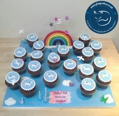 there are many cupcakes on the table ready to be eaten with rainbow in the background