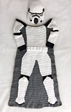 a crocheted star wars costume laying on top of a white sheet with a teddy bear