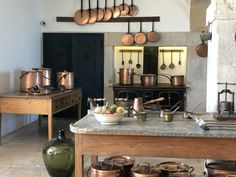 an old fashioned kitchen with pots and pans hanging from the ceiling, on display