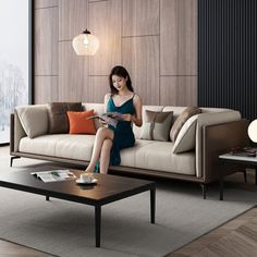 a woman sitting on a couch in a living room next to a coffee table and lamp