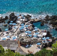 many umbrellas are set up on the rocks by the ocean