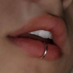 a close up view of a person's lips with their nose ring in the foreground