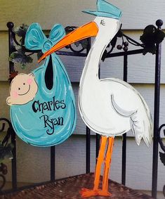 a stork holding a baby in a blue bag on top of a gate