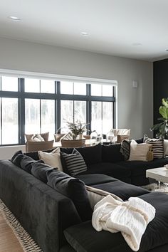 a living room filled with black couches and white tables in front of large windows