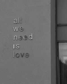 the words all we need is love are written on the side of a building in black and white