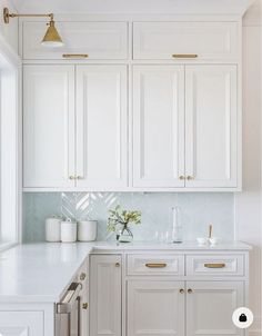 a kitchen with white cabinets and gold pulls