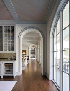 a long hallway leading to an open kitchen and living room with lots of glass doors